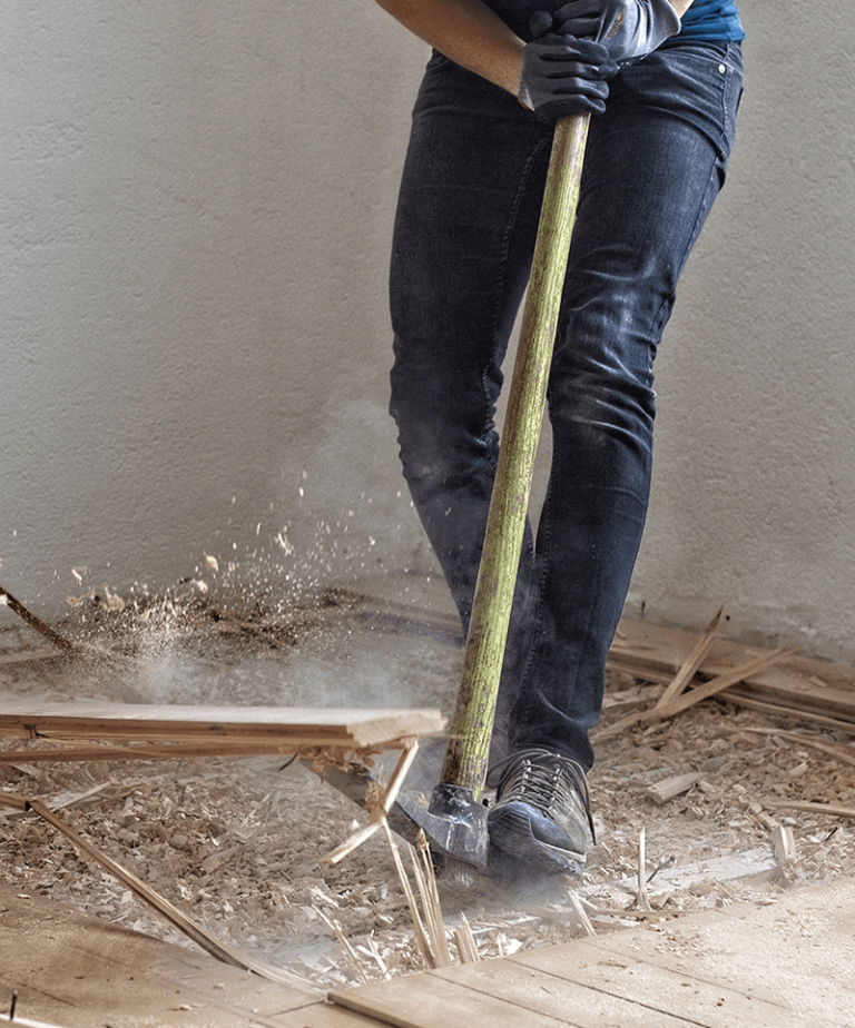 Worker breaking up old flooring with a sledgehammer during a property refurbishment